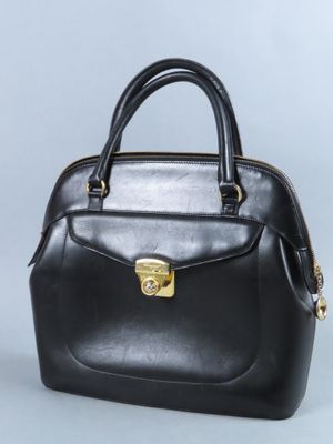 sac à main en cuir noir avec des finitions dorées sur fond gris