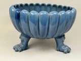 un grand bol bleu sur pied posé sur une surface blanche