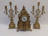 a gold clock sitting next to three candles on a table