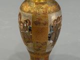 a gold vase with a design on it on a gray surface