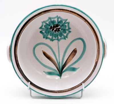 a small bowl with a flower on it on a stand