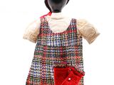 un mannequin coiffé d'un chapeau rouge et vêtu d'une robe à carreaux