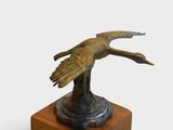 bronze statue of a bird on a wooden base on a white background