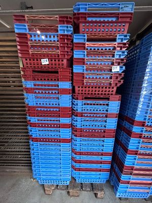 plusieurs caisses en plastique bleues et rouges empilées dans un entrepôt