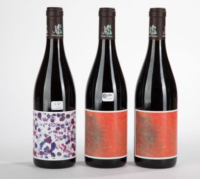 trois bouteilles de vin ornées de motifs différents sur fond blanc