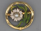 une image représentant une broche ornée d'une fleur et d'une perle au centre