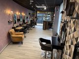 a photo of a hair salon with chairs and mirrors