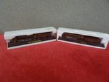 deux petits trains miniatures posés sur une table rouge