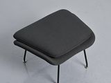 gray ottoman with metal legs and a black cushion on a white floor