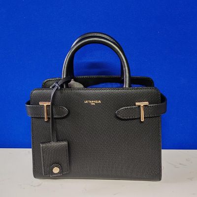 a small black purse with a gold handle on a table