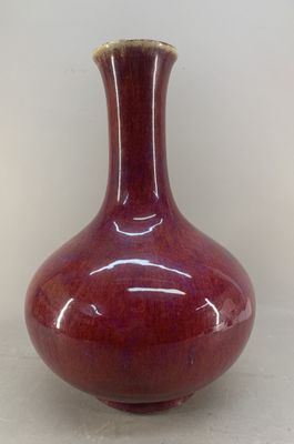a red vase sitting on a table with a white wall in the background