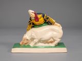 figurine of a man riding a pig on a green base