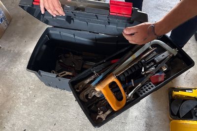 a man that is holding a tool box with tools in it