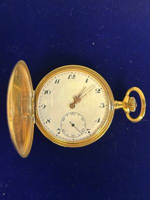 une image représentant une montre de poche en or posée sur une surface bleue