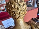 a gold statue of a man in a room with a red wall