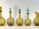 four different colored glass vases sitting next to each other on a white surface