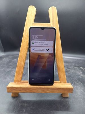 un téléphone portable posé sur un support en bois, sur une table