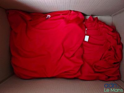 un t-shirt rouge dans une boîte sur laquelle est accrochée une étiquette