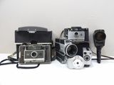 several old cameras are lined up on a white surface