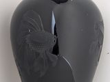 a black vase with a bird on it on a shelf