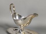 an antique silver plate with a saucer and spoon on it