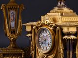 a clock on a table next to a three candle holder