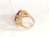 a close up of a gold ring with a purple stone in it