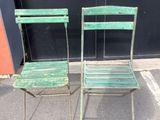 two green chairs sitting next to each other in a parking lot