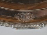 a silver plate on a table with a clock on top of it