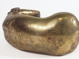 a gold statue of a dog laying down on a white surface