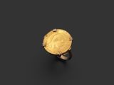 une image représentant une bague en forme de pièce d'or sur laquelle est gravé le visage d'une femme