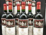 six bouteilles de vin rouge sont alignées sur une table noire