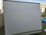 a white refrigerator sitting on the grass in front of a building