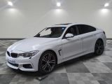 La BMW M4 berline blanche est garée dans une grande pièce.