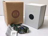 une photo d'une montre posée à côté d'une boîte en carton sur une table