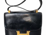 un sac à main en cuir noir avec des finitions dorées sur fond blanc