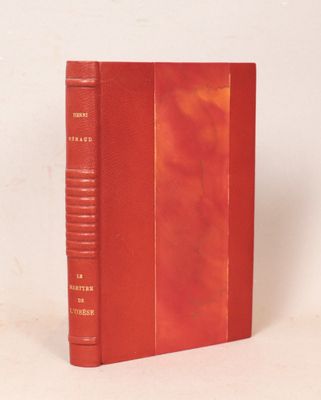 un vieux livre rouge posé sur une table à côté d'un mur blanc