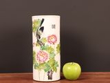 a vase that has a bird on it next to a green apple