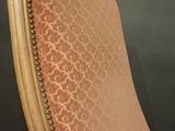 an old chair with a pink upholstered seat and a wooden frame