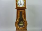 une horloge de parquet posée sur un socle devant un fond blanc