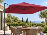 une photo d'une terrasse avec une table et des chaises sous un parasol rouge