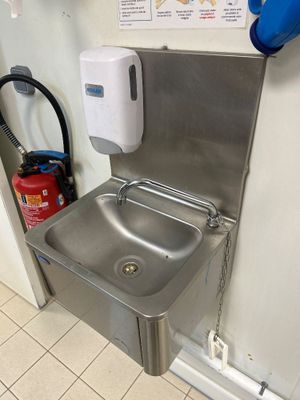 un évier en acier inoxydable avec un sèche-mains fixé au mur
