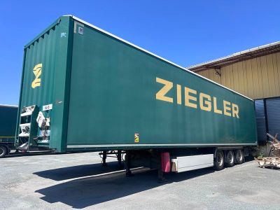 un grand camion vert garé devant un immeuble