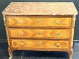 an antique chest of drawers with marble top and brass handles
