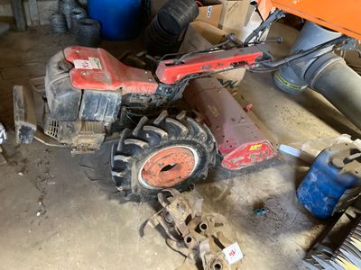 un tracteur qui se trouve dans un garage, à côté d'un tas d'outils