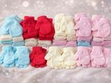 many pairs of baby mittens on a white blanket