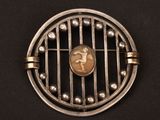 une broche ancienne en argent représentant une femme dans une cage