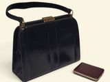 a black purse and a cell phone on a white surface