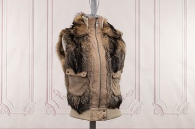 a fur vest on a mannequin stand in front of a wall