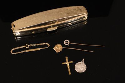 a gold plated case with a key, chain, and other items